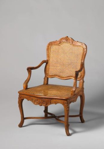 Armchair of walnut and beech wood with S-shaped splayed legs; X-shaped cross with rosette; carved floral and foliate work, wicker back and seat, with loose cushion