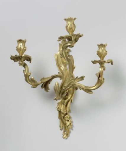 Wall arm of gilded bronze with three arms. Stem and arms are composed of asymmetrical C- and S-shaped leaf motifs with flowers incorporated at the bottom.