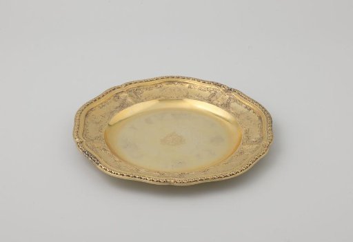 Underplate of gilt silver, with slightly lobed rim. Decorated with five panels with putti between dead game, birds and hunting attributes.