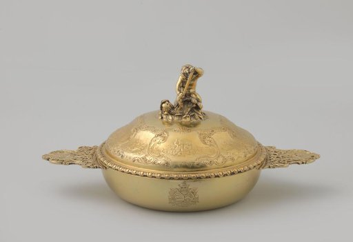 Covered dish of gilt silver, flat and round, with lid and two horizontal handles with fishing gear, reeds and fish. On lid among others boy with a dolphin and dolphins on putti.