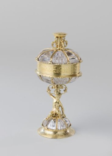 Lidded dish with mount of gilded silver. On a dome-shaped foot a naked youth who with one hand holds the mount of the vessel.