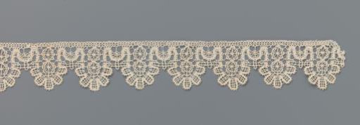 Strip of bobbin lace with wheels and five-lobed shells