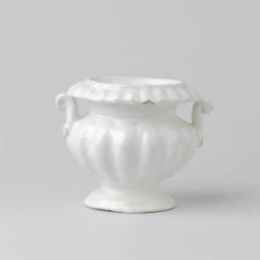 Salt cellar with lobed rim and wall, with two volute-shaped ears, on a foot with a downward-overhanging rim. Undecorated.