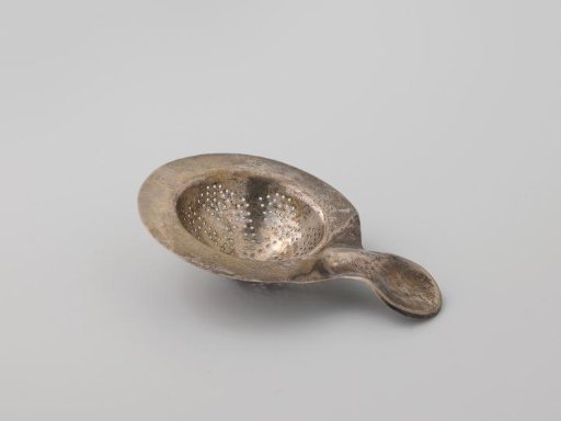 Tea strainer of silver, round, with broad smooth rim and short handle with thumb rest