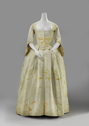 Overjapon with Watteau pleat of cream-colored silk, embroidered in yellow with slender, widely spread flower and leaf vines.