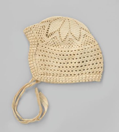 Crocheted white cotton children's cap, with openwork and an outer edge consisting of three scalloped edges; floral motif at the back