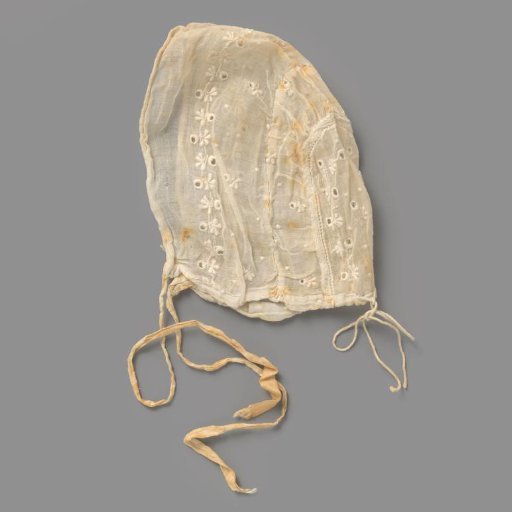 Children's cap of sheer woven white cotton with a white embroidered scattering motif and flower and leaf vines along the back and front; front and back two ribbon bows