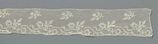 Strip of bobbin lace with a row of loose flower branches and, along the underside, linked fields formed by a sparse vine