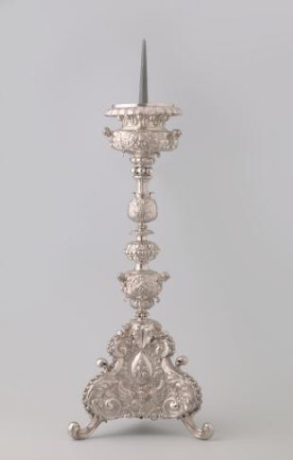 Silver candelabrum with five-sectioned baluster stem on triangular base on scroll feet. Decorated with medallions containing Christ, Peter, and Ignatius