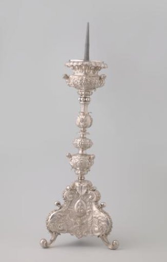 Silver candelabrum with five-sectioned baluster stem on triangular base with scroll feet. Decorated with medallions containing Christ, Peter, and Ignatius