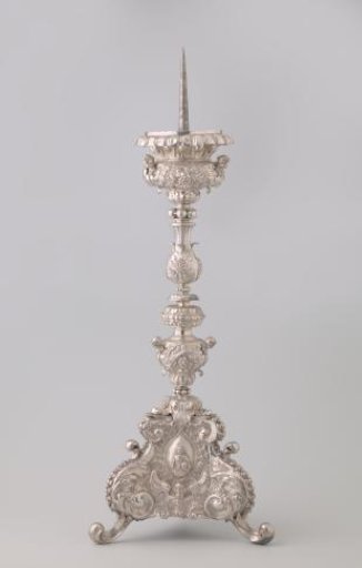 Silver candelabrum with five-part segmented baluster stem on triangular foot with volute feet. Decorated with three medallions containing Christ, Peter, and Ignatius