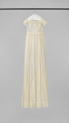 Baptismal gown of white batiste with embroidery of winding branches with foliage and loose marguerites