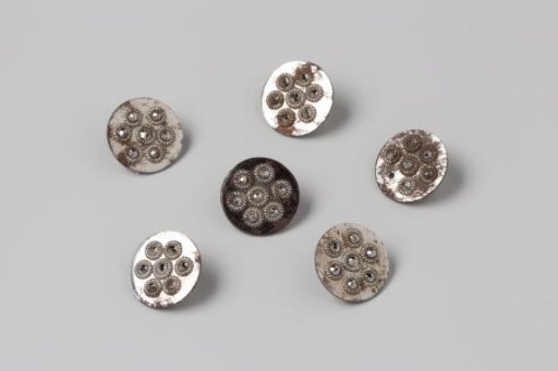 Six buttons of ground steel on a smooth ground, with seven diamond-headed studs
