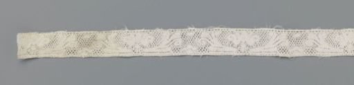 Ornamental insert of bobbin lace with flower between elongated volute leaves