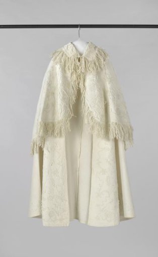 Child's cape of white piqué, decorated with soutache along the front and hem.