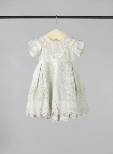 Child's dress of white cotton with a woven rib, decorated with soutache, English embroidery and passementerie.