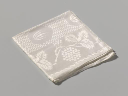 Tablecloth with border of grapevines and a checkered center with inserts