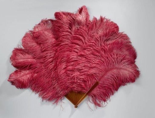 Folding fan with bright pink ostrich feathers on an unadorned plastic mount with tortoiseshell pattern