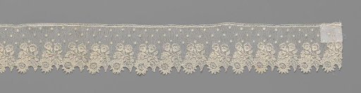 Strip of needle lace with a horizontal branch with three flowers amongst mosses