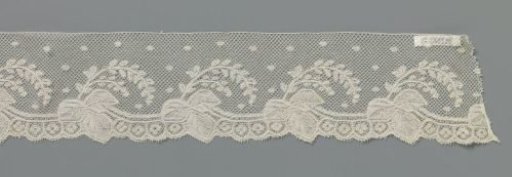 Strip of bobbin lace with grape leaf on a curved stem