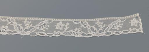 Strip of bobbin lace with carnation between V-shaped fields