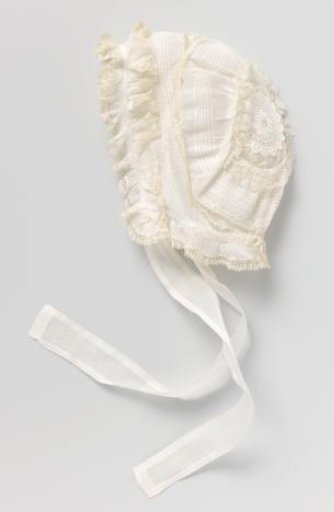 Cap of white batiste with gathering and lace strips and two ribbon ties of the fabric; on the back a rosette of white embroidery