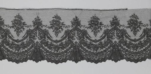 Japanese strip of black bobbin lace with three feather-shaped leaves under oval cartouches and rose garlands