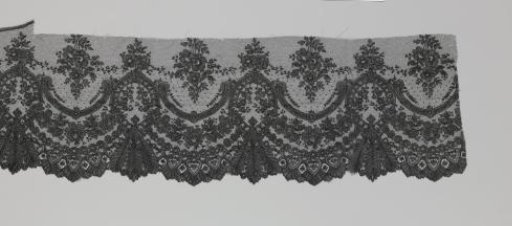 Strip of Japanese black bobbin lace with three feather-shaped leaves under oval cartouches and rose garlands