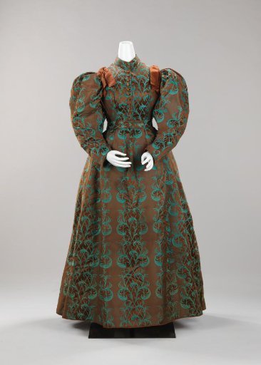 Japanese kimono with long puffed sleeves, button closure, sash, and standing collar of brown silk with blue-green ostrich feather motifs; a brown satin bow on the shoulders
