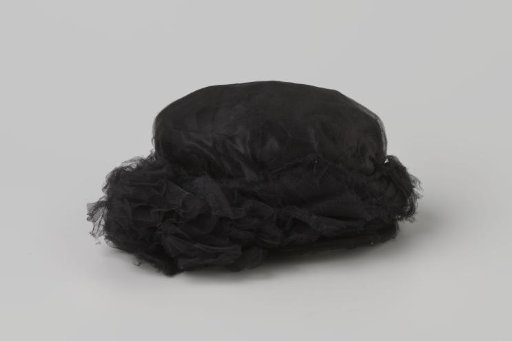 Hat of black tulle and satin with a tuft of tulle on the right, with a hatpin with a pea-shaped knob of straw