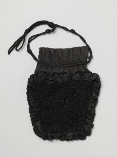 Reticule in trapezoidal sections, of black crocheted silk, bordered with black ruffles of pongee silk