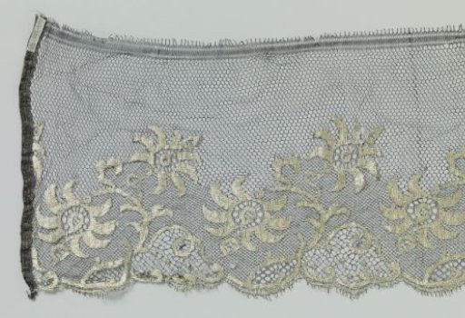 Strip of machine-made lace with black ground and natural-colored motifs