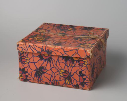 Square hat box of cardboard, covered with Art Deco paper with an orange ground featuring a whimsical pattern in blue and flowers in black, yellow, and red