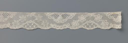 Strip of bobbin lace with an arch of six-petaled flowers and fan