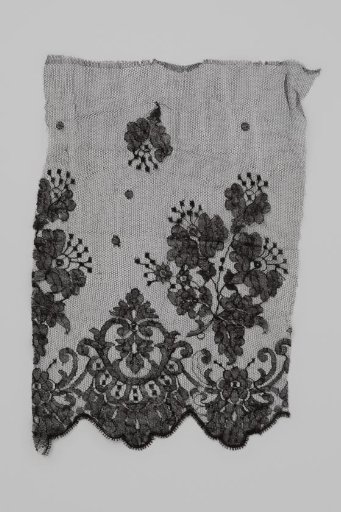 Piece of black machine-made lace with a scalloped edge; with a palmette pattern