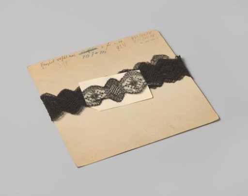 Strip of double-sided carved black machine-made lace, on cardboard