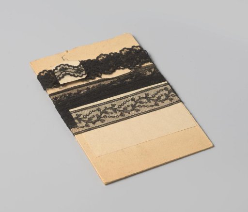 Insert of black machine-made lace with a continuous scrolling leaf motif, on cardboard