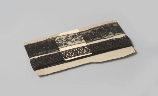 Insert of black machine-made lace with scrolling flower and leaf motif, on cardboard