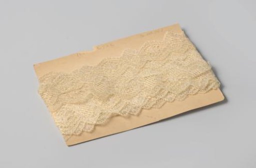 Strip of white machine-made lace, scalloped, on cardboard