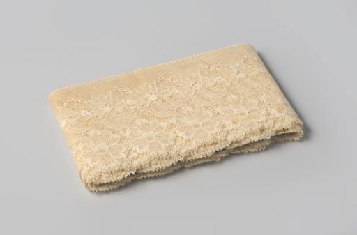 Strip of white machine-made lace with flowers scalloped on one side, on cardboard