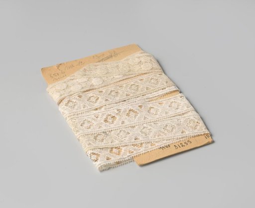 Insert of white machine-made lace with a pattern of flowers and circles, on cardboard