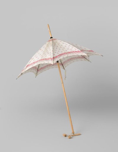 Parasol covered with a canopy of white printed cotton with a scattered pattern of pink roses on a light wooden shaft