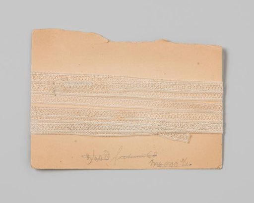 Insert of white lace with strung wheels on cardboard