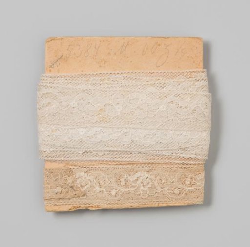 Insert of white lace with a floral motif on cardboard