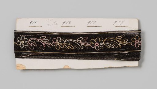 Cardboard with an insert of black lace with pink, yellow and white contour threads around the floral decorations and borders