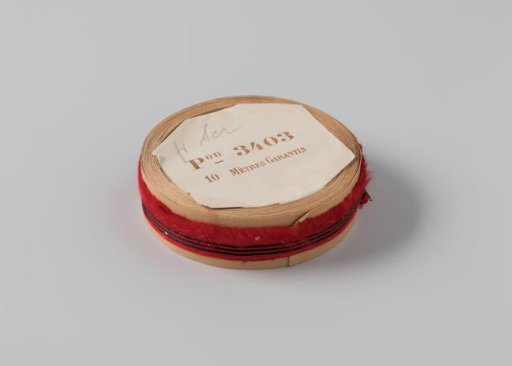 Roll with red ribbon, one frayed side and three black horizontal stripes
