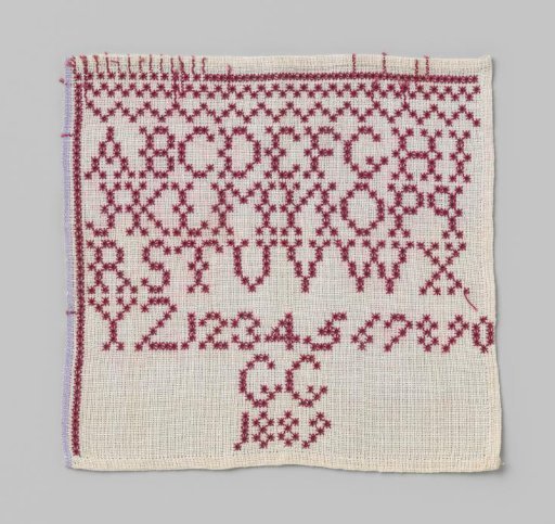 Linen sampler with a grid of red letters and numbers; marked: GG 1889.