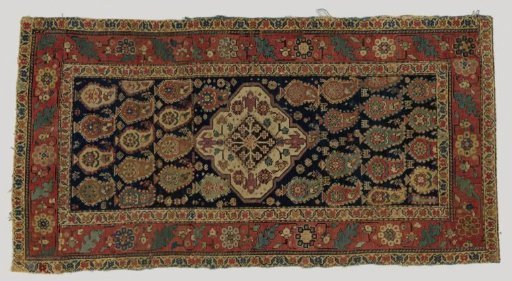 Medallion carpet, decorated with botehs on a blue ground and geometric motifs and animal figures. Cherry-red border with S-shaped scrolls and rosettes.