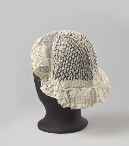 Cap with a crown of Frisian lace in fine knitting, trimmed with a strip of tulle decorated with needlework; the strip is pleated along the forehead