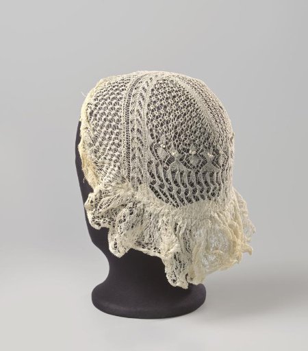 Cap of Frisian lace in fine knitting; the brim is gathered along the forehead and set on the crown